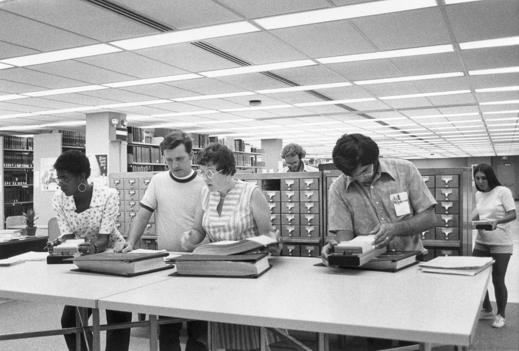 Miniature of Students using card catalog with help of librarian